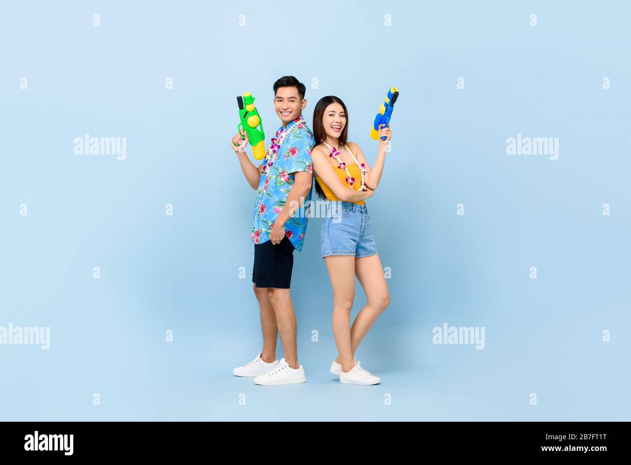 Giovane coppia asiatica in estate abiti con cannoni ad acqua in studio sfondo blu per Songkran festival in Thailandia e sud-est asiatico Foto Stock