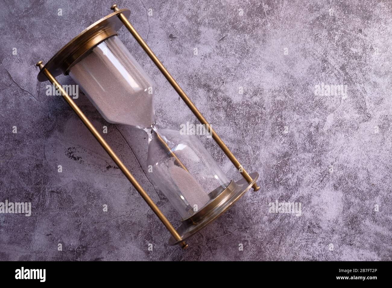 Sabbia che scorre attraverso le lampadine di una clessidra che misura il tempo che passa Foto Stock