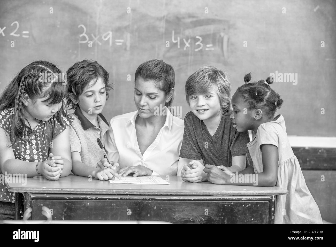 Insegnante femminile che spiega la matematica alla classe multietnica primaria. Foto Stock