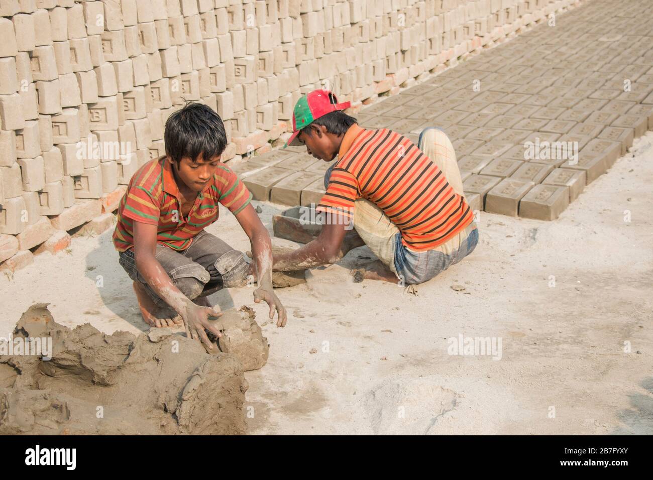 Un lavoro minorile del Bangladesh sta lavorando in un mattone archiviato sotto una giornata di sole. Anche se il lavoro minorile è limitato in questo settore, ma sta lavorando per il cibo. Foto Stock