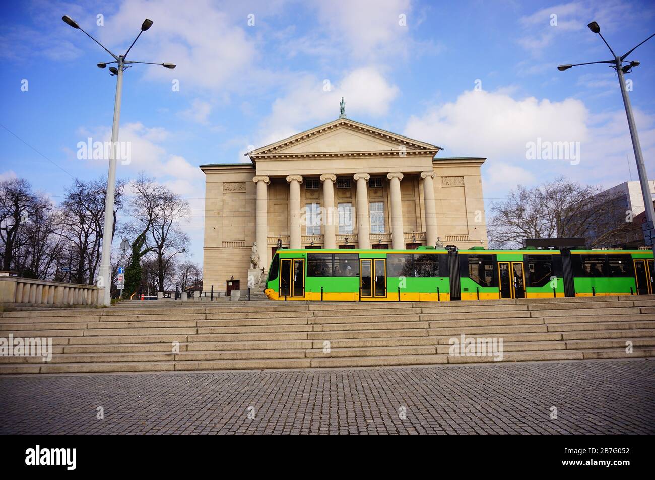 POZNAN, POLONIA - 05 marzo 2020: Tram verde che si sposta di fronte all'edificio del Gran Teatro nel centro della città. Foto Stock