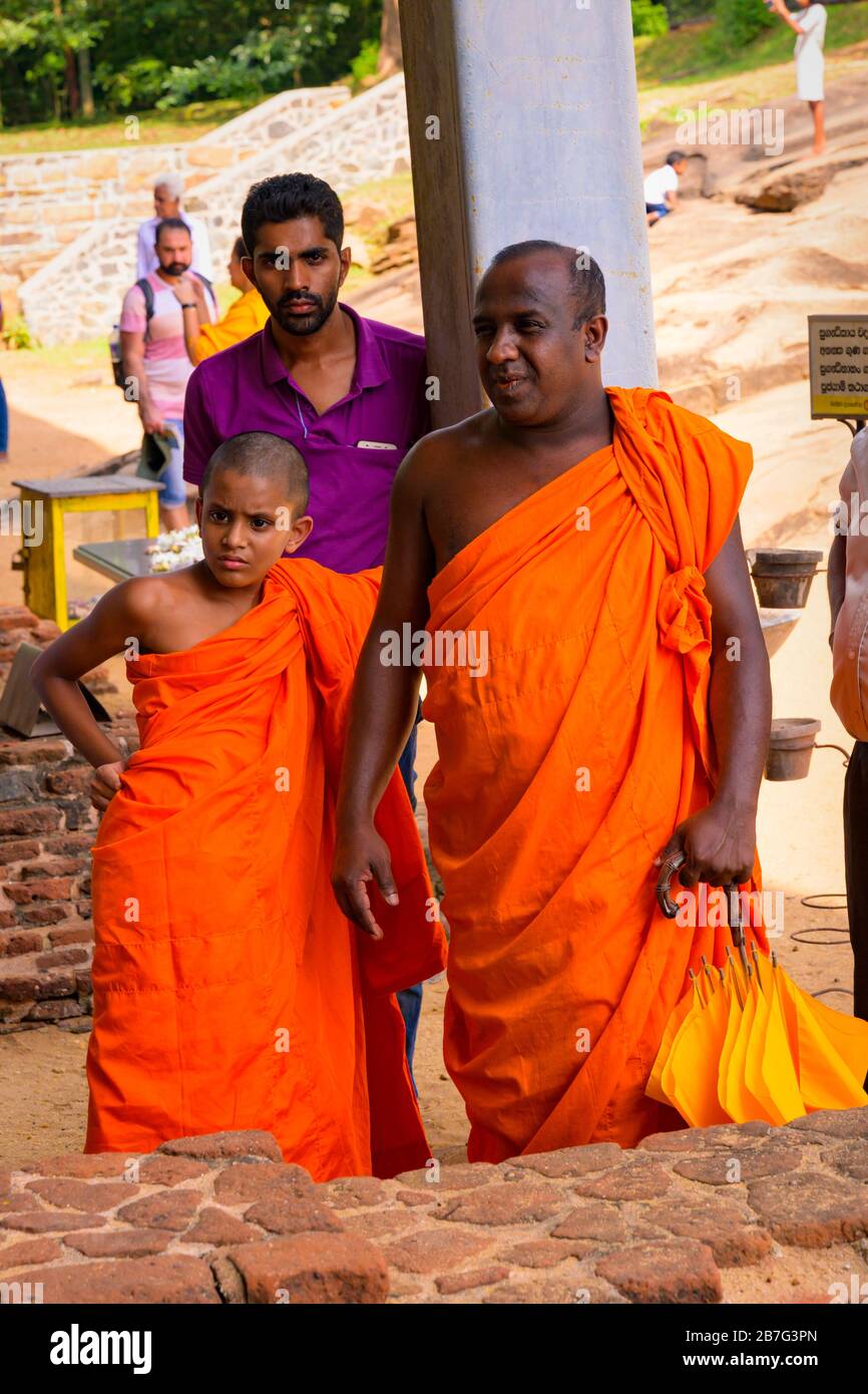 Sri Lanka Ceylon Triangolo Culturale Anuradhapura Polonnaruwa Gal Vihara Santuario buddista monaco monaci padre figlio zafferano rosso abiti abitudini Foto Stock