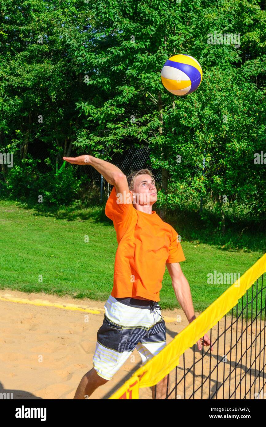 Gioco intensivo sul campo di beachvolley, uomo che fa un smash Foto Stock