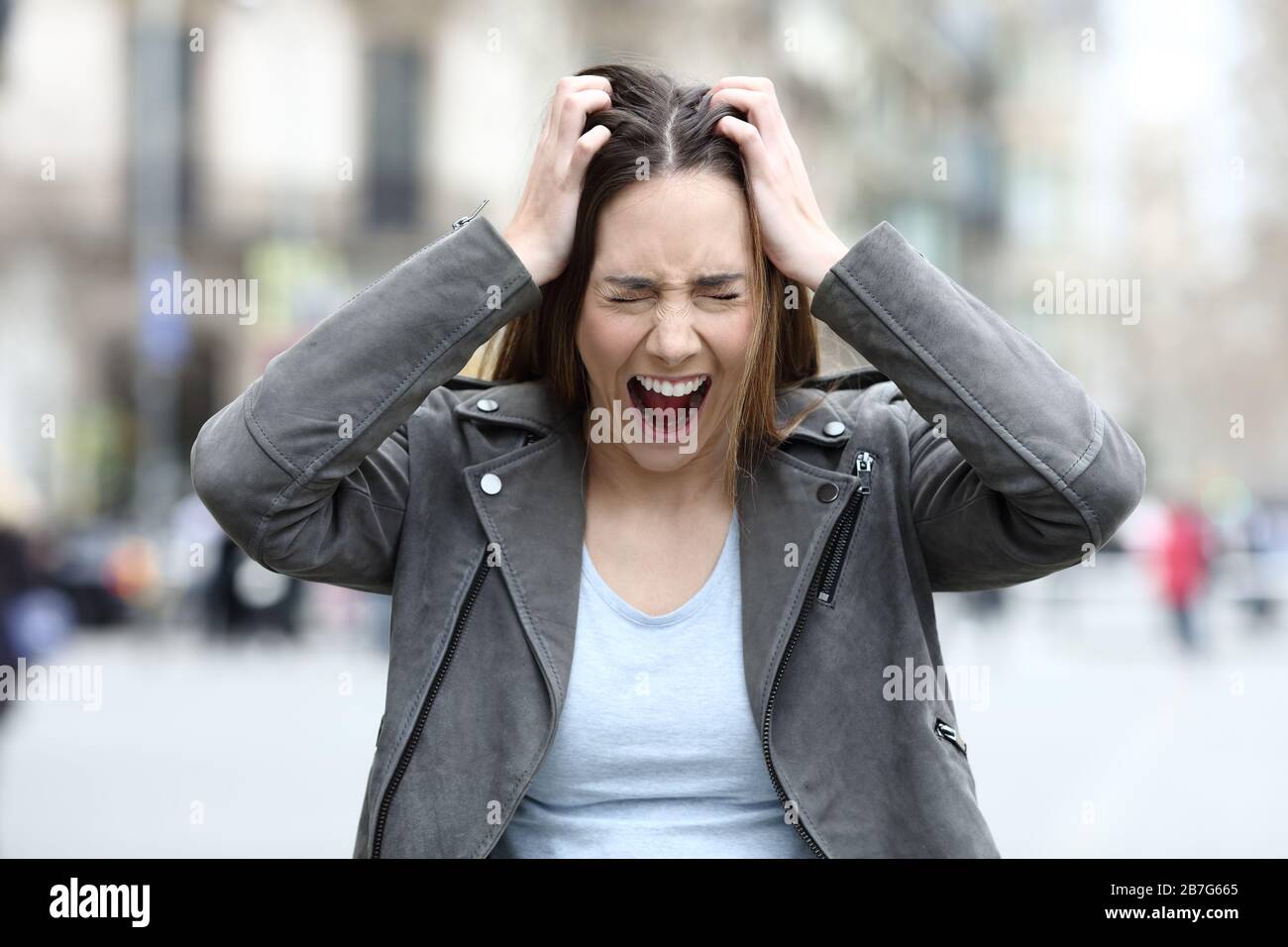 Vista frontale ritratto di una donna disperata e ansiosa che urla sulla strada della città Foto Stock