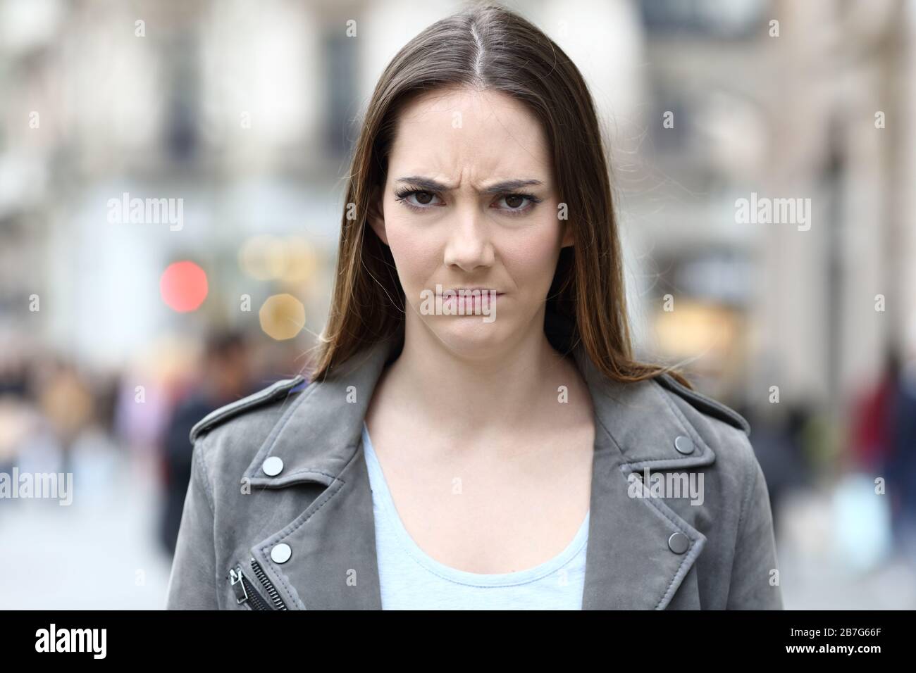 Vista frontale ritratto di una donna arrabbiata che guarda infastidito alla macchina fotografica sulla strada della città Foto Stock