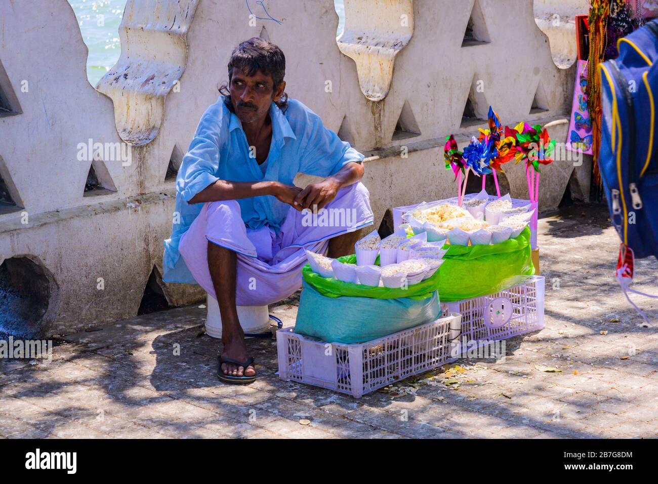 Asia meridionale Sri Lanka Kandy Singhala Provincia Centrale antica capitale marciapiede venditore popcorn colorato giocattolo mulini a vento bianco muro Foto Stock