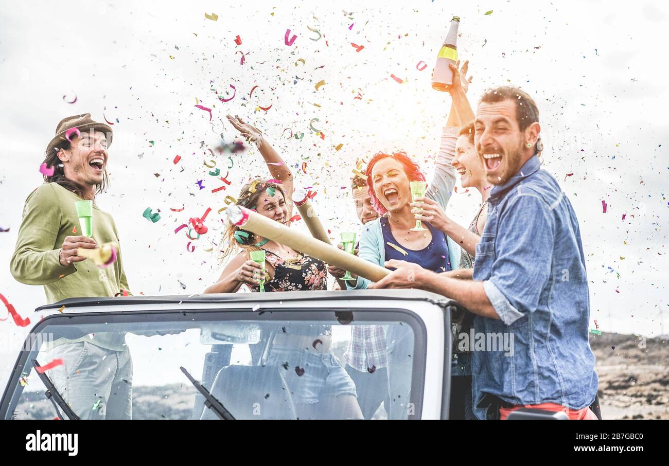 Party gente divertimento su auto 4x4 convertibile lancio di confetti e bere champagne - amici trendy ridere insieme in vacanza estiva - Viaggi Foto Stock