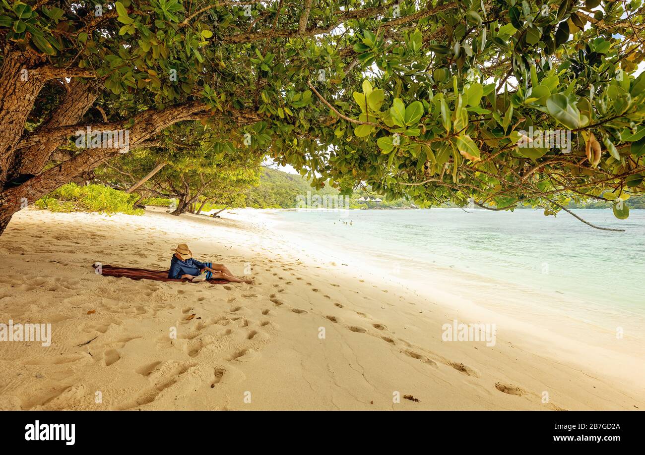 Bell'uomo sdraiato sulla spiaggia e libro di lettura. Ora legale. Turista rilassarsi su una spiaggia tropicale Foto Stock
