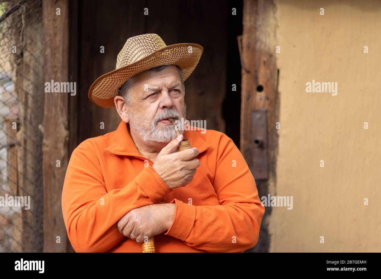 Ritratto di caucasico senior con tubo di tabacco contro l'antica casa ingresso Foto Stock