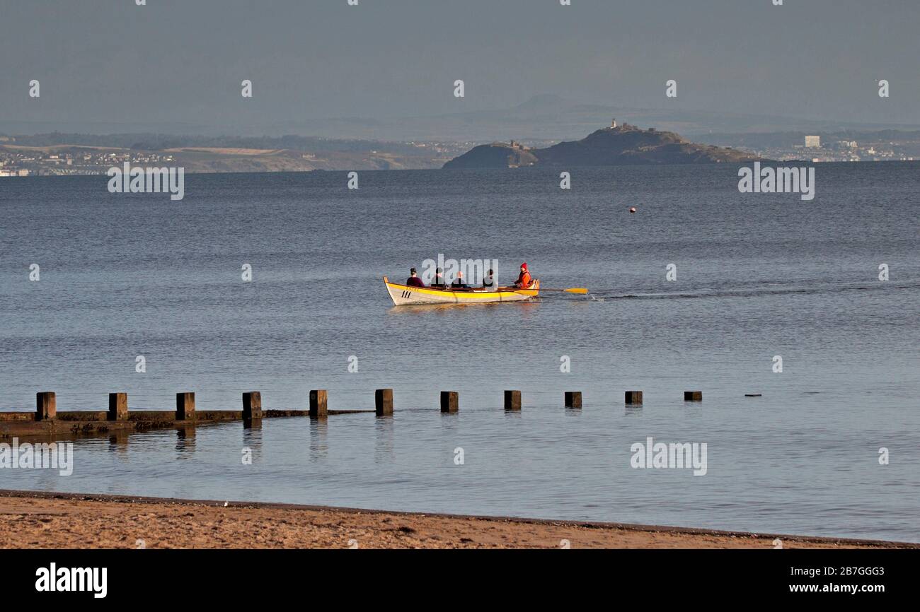 Portobello Beach, Edimburgo, Scozia, Regno Unito. 16 Mar 2020. La gente che mantiene calma e che continua con le loro normali procedure. Attività mattutina al mare. Tempo, luce solare nebulosa con temperatura di 3 gradi dopo una notte molto fredda, pioggia prevista da ovest più tardi. Eastern Amateur Rowing Club out per excercise con l'isola di Inchkeith e costa di Fife in background. Foto Stock