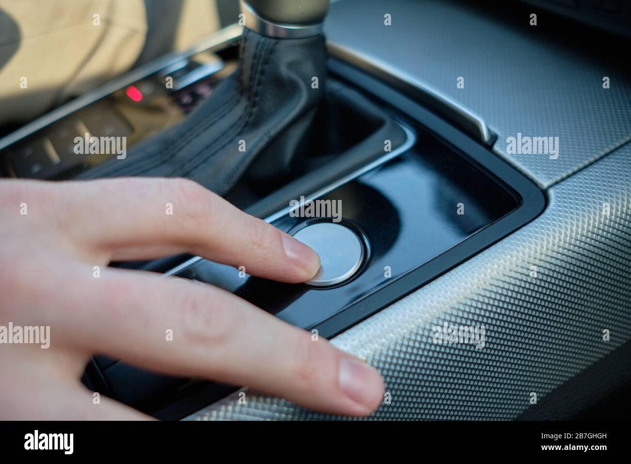 Un uomo in una macchina moderna. La mano inserisce l'accensione. Primo piano. Foto Stock