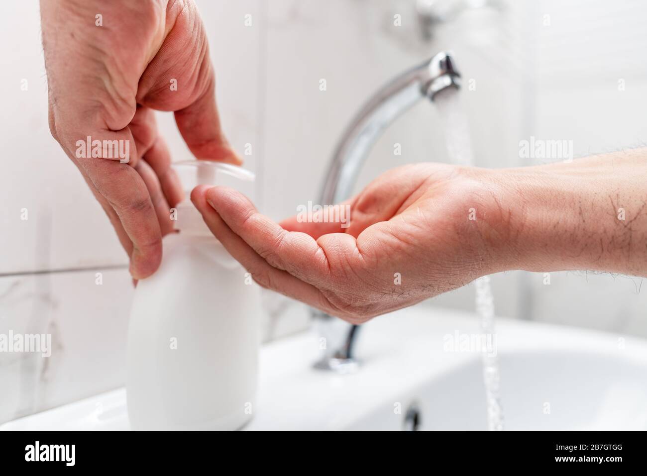 Igiene personale, pulizia delle mani con sapone spesso sul rubinetto per proteggere dal virus Foto Stock