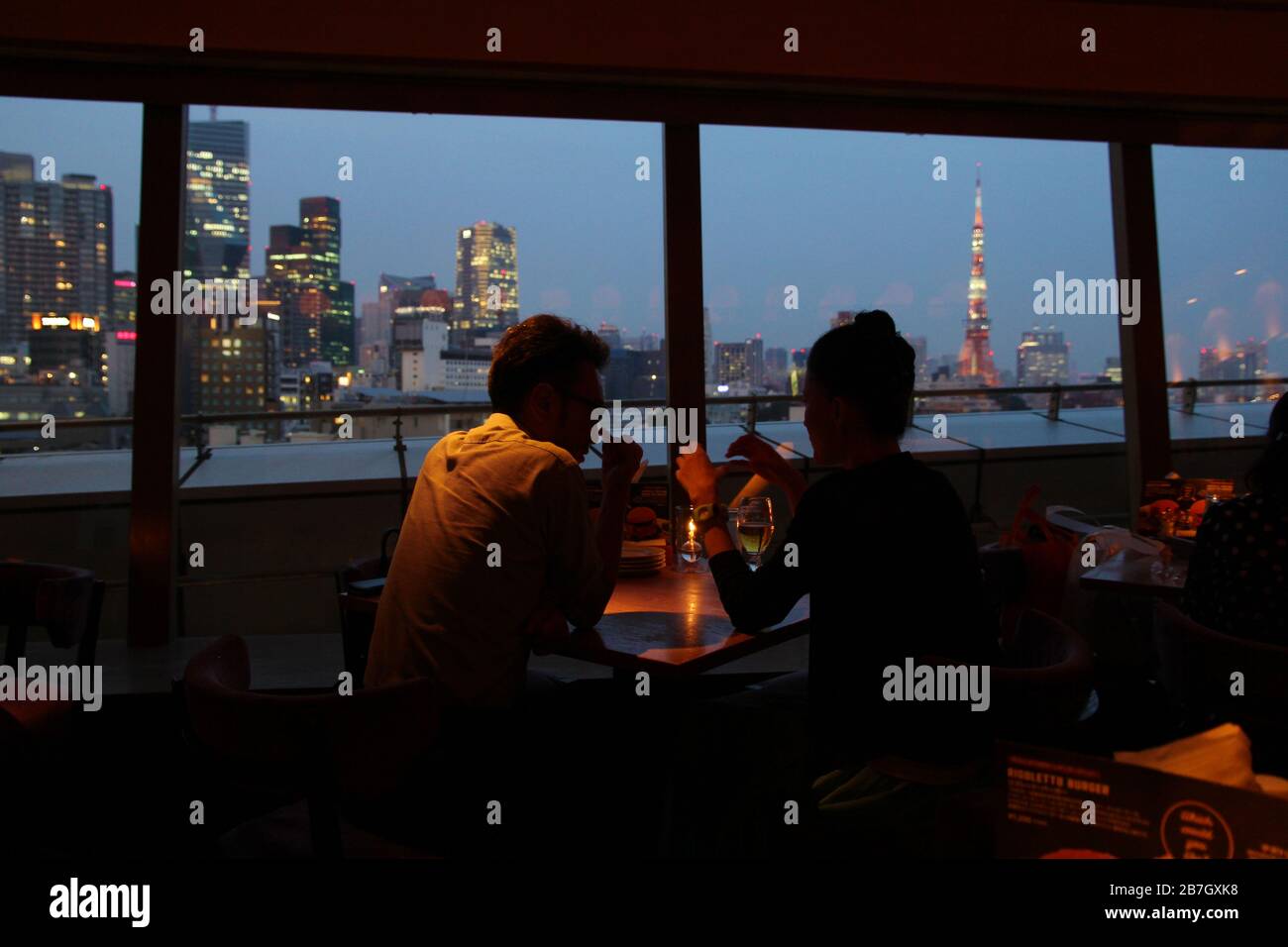 Coppia giapponese che si è data in un romantico bar con una bella vista notturna sulla città di Tokyo Foto Stock