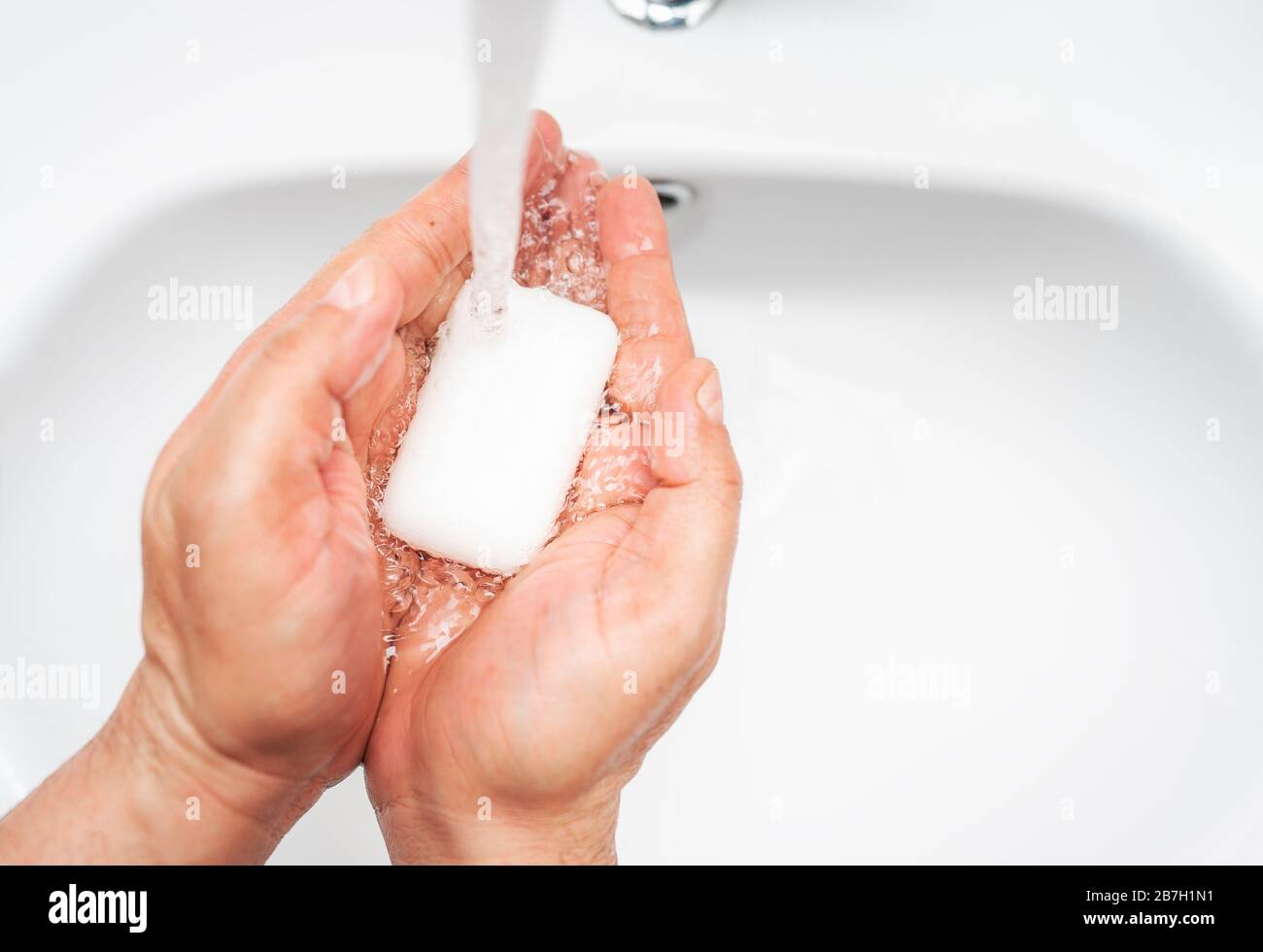 Igiene personale, pulizia delle mani con sapone spesso sul rubinetto per proteggere dal virus Foto Stock