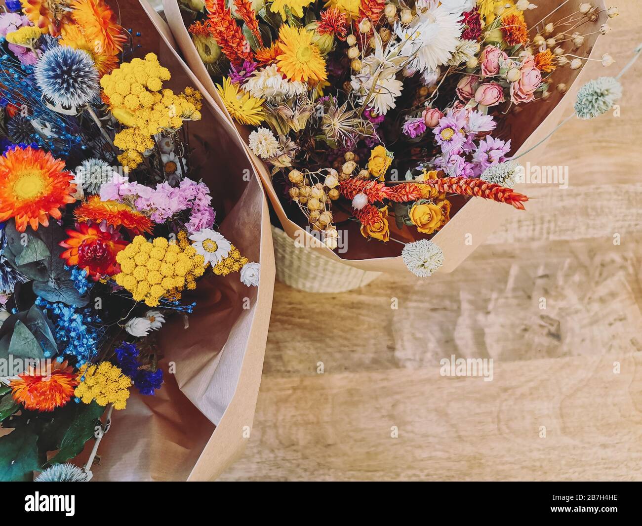 Vivace composizione di fiori secchi in rosso, giallo e viola su uno sfondo di legno Foto Stock