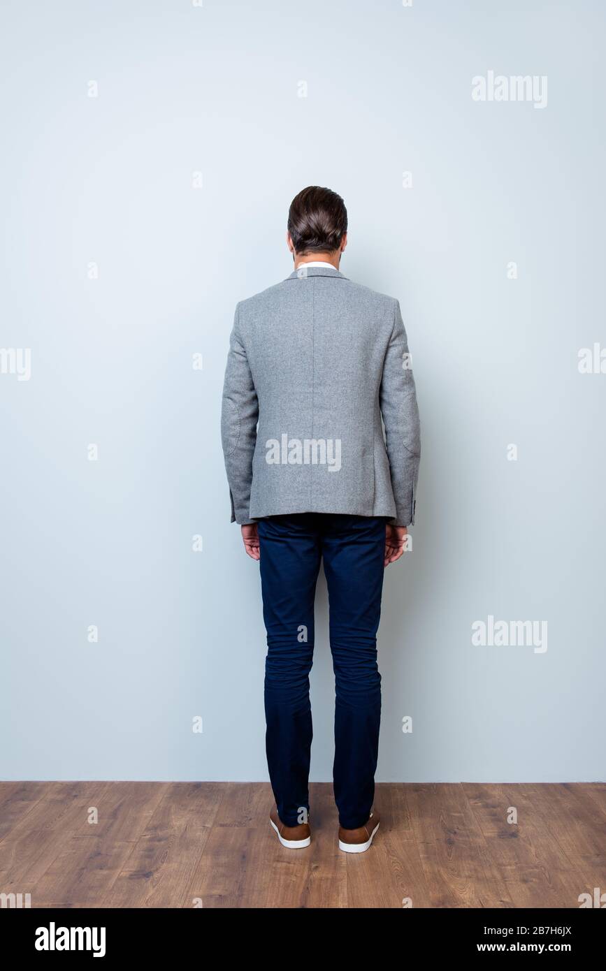 Verticale sul retro: Ritratto a figura intera dell'uomo con giacca grigia e  pantaloni blu scuro su sfondo grigio Foto stock - Alamy