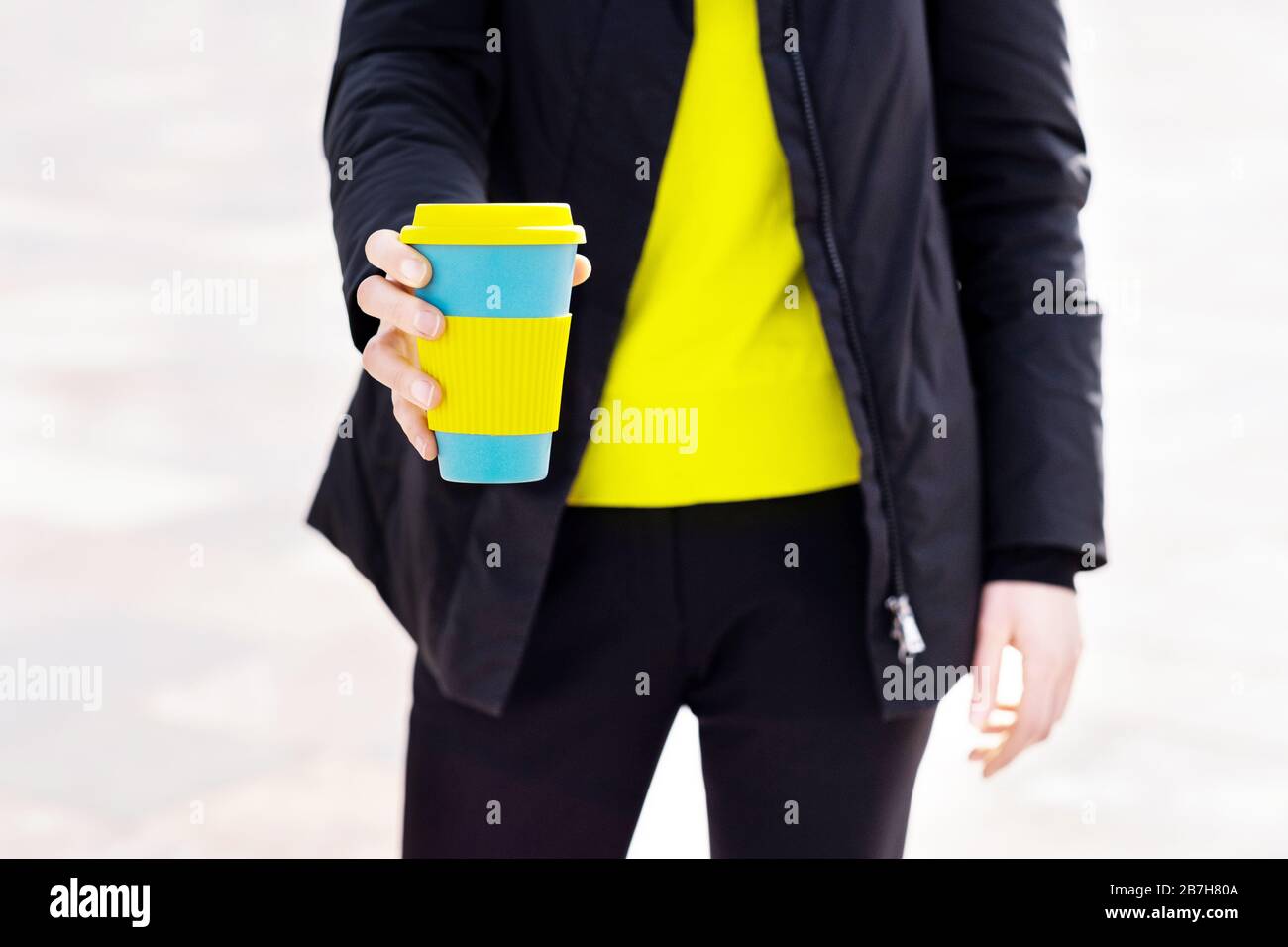 Le mani femminili trattengono una tazza di caffè riutilizzabile. Porta il tuo caffè sempre con te con una tazza riutilizzabile. Foto Stock