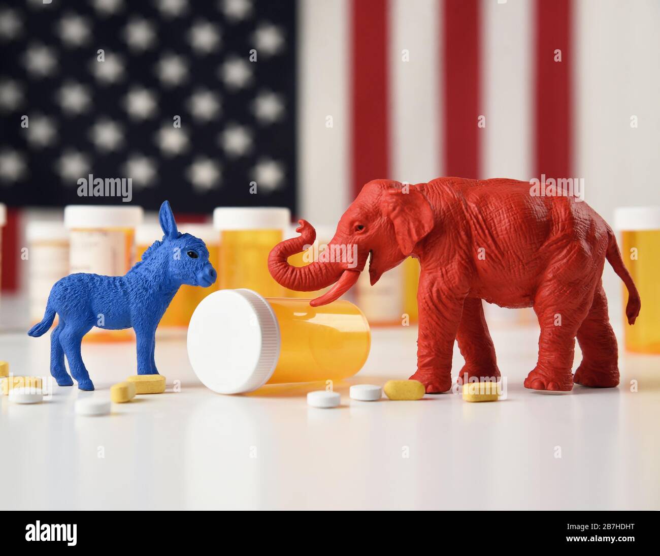 Un asino blu come democratico e un elefante rosso come repubblicano sono contro una bandiera americana con bottiglie di pillola prescrizione per un concetto di costo medico Foto Stock