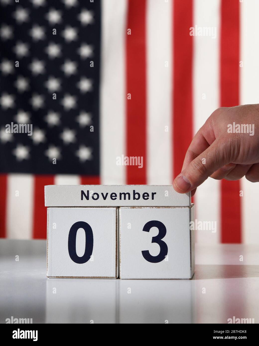 Una mano sta salvando la data del novembre 3 2020 per le elezioni presidenziali democratiche con una bandiera americana sullo sfondo di un concetto di elettore. Foto Stock