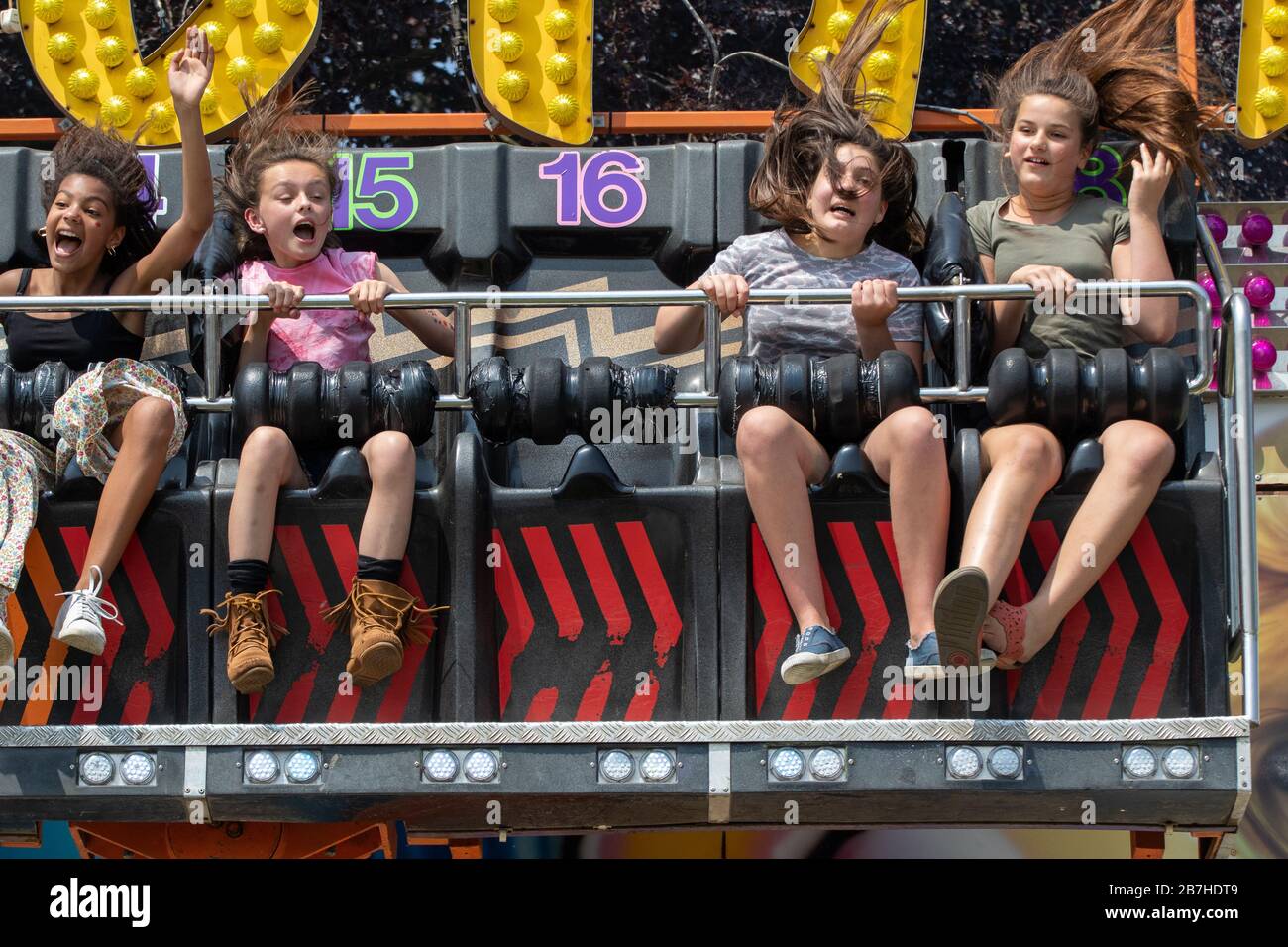 I capelli volanti delle ragazze adolescenti su un divertente giro in fiera Foto Stock