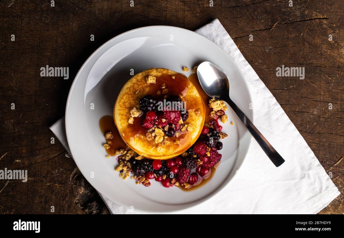 Vista dall'alto di pancake con frutti di bosco bacche su tavolo di legno. Mirtilli, lamponi su frittelle. Concetto mattina proteina prima colazione. Foto Stock
