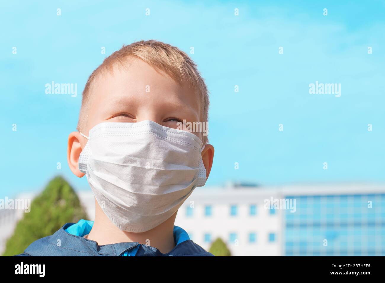 Ragazzo carino europeo in una maschera medica protettiva all'aperto in una chiara giornata di sole. Prevenzione delle malattie virali, concetto di protezione dai virus. Foto Stock