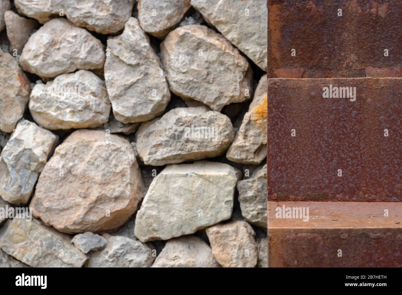 Primo piano di un gradino arrugginito di una scala accanto a un muro di pietra Foto Stock