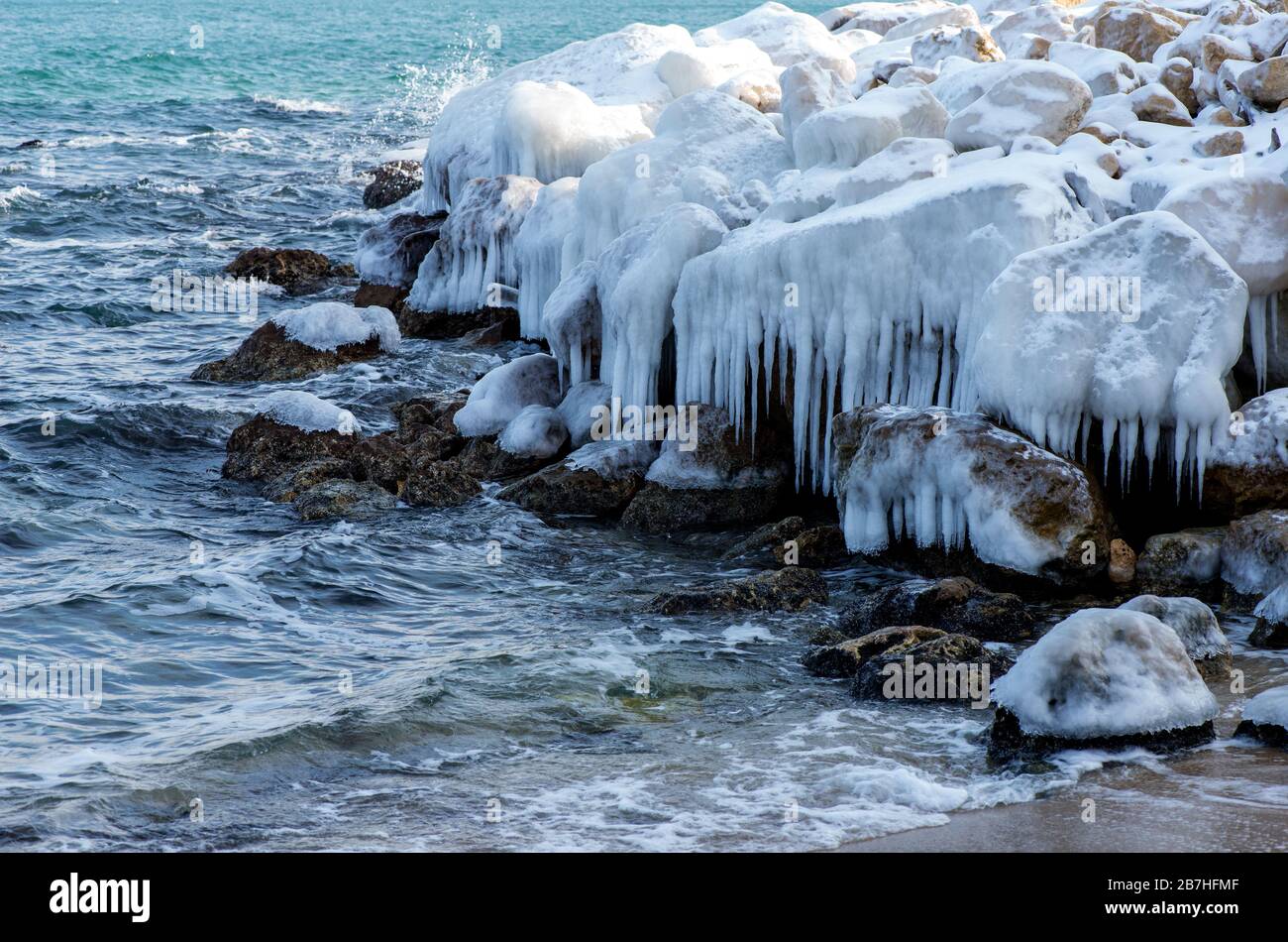 L'inverno si disegna su rocce marine e ghiaccioli Foto Stock