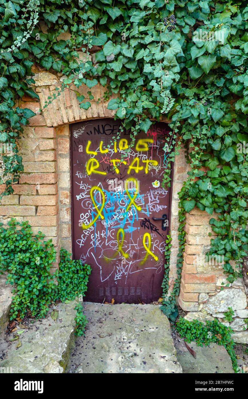 Piccola porta viola con graffiti e edera nella cittadina di Collbato sulle pendici di Montserrat, Barcellona, Spagna Foto Stock