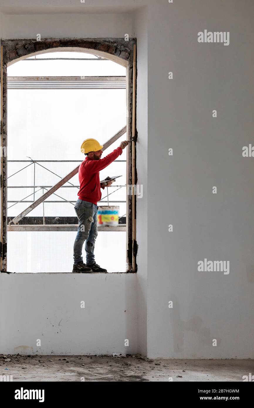 Worker bilanciamento su una finestra durante il lavoro. Cantiere Foto Stock