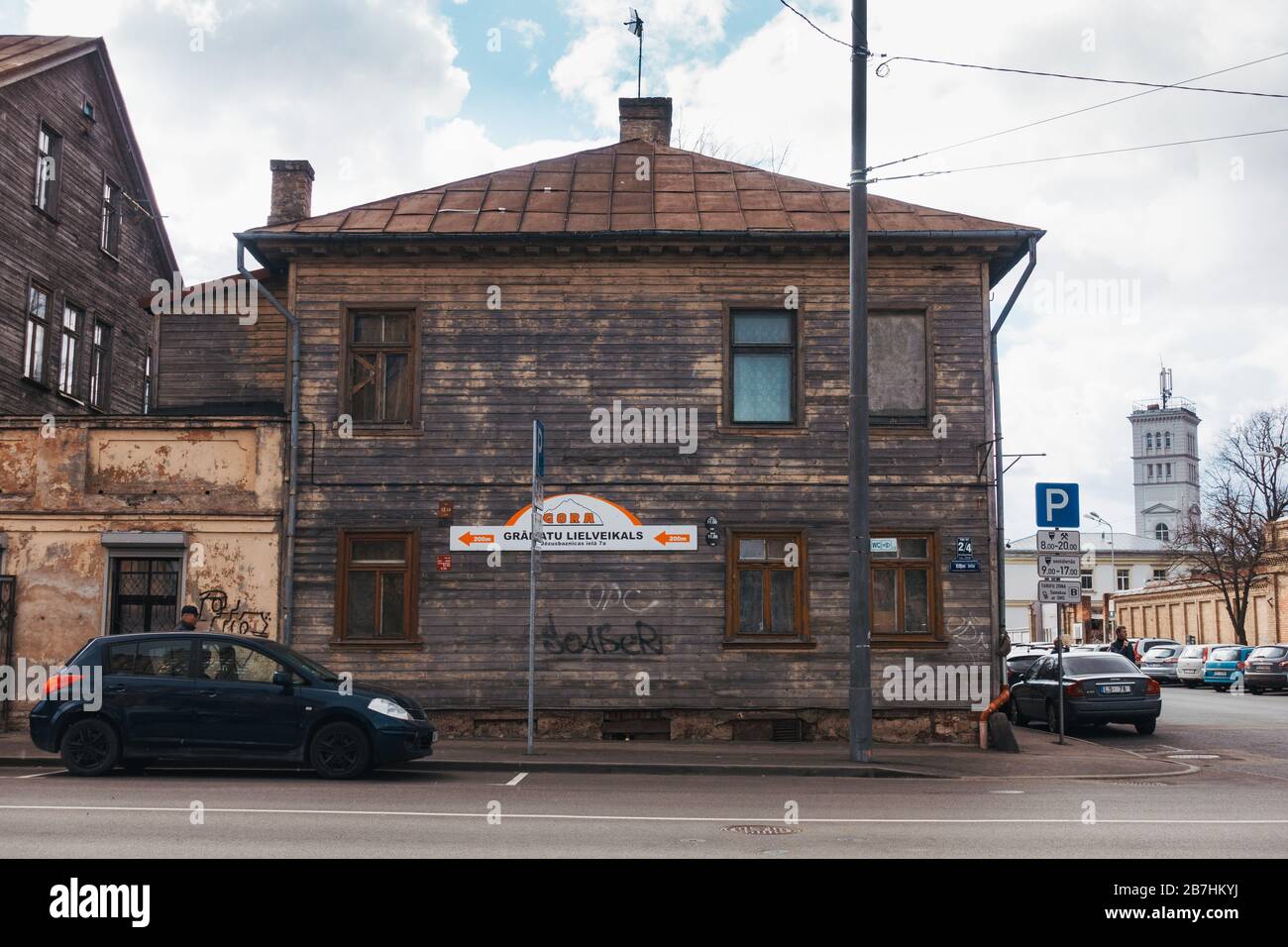 Auto parcheggiate sulla strada di fronte ad una vecchia casa di legno a due piani a riga, Lettonia Foto Stock