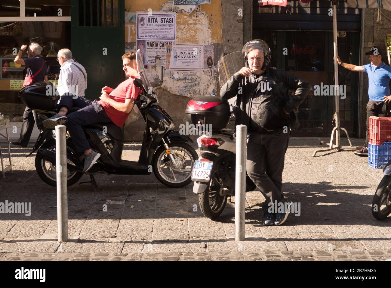 Una scena di persone che si rilassano al sole in una strada di Napoli, Italia. Foto Stock