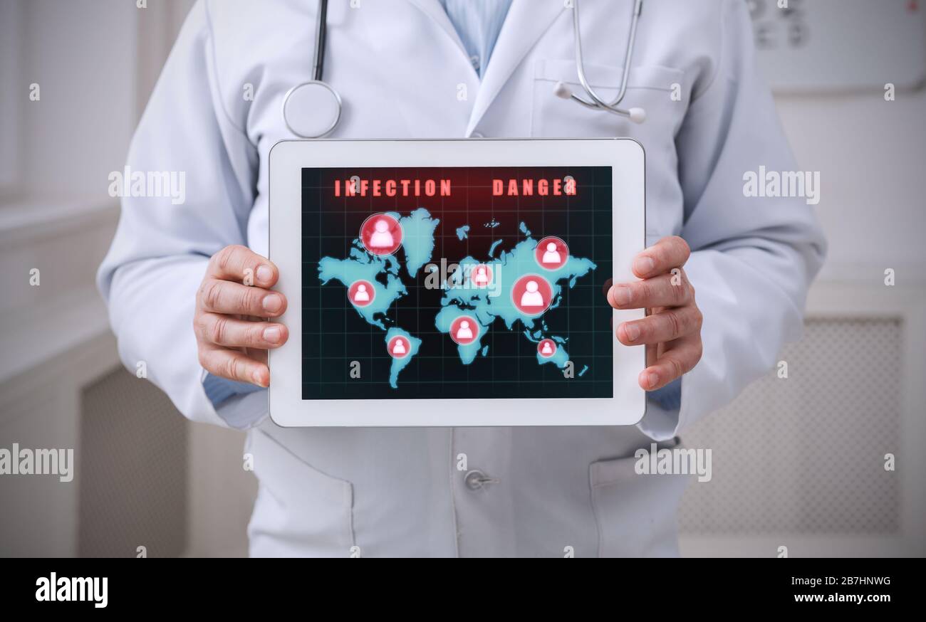 Il medico che tiene un tablet con la mappa del mondo coperta in zone di infezione da quarantena sullo schermo Foto Stock