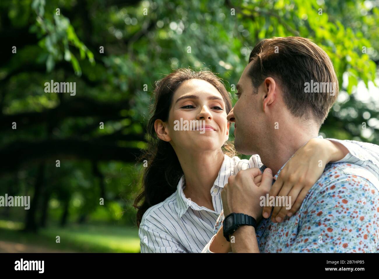 Ritratto sorridente giovane uomo e donna giovane in amore abbracciando nel parco di stagione estiva con il caldo sole. Le persone e il concetto di stile di vita. Foto Stock