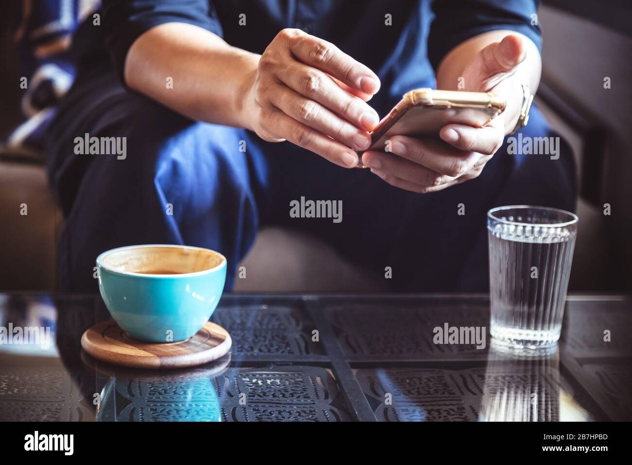 Imprenditore utilizza lo smartphone per leggere notizie di investimento e mail di risposta a conferma riunione in coffee shop. l uomo di bere latte caffè prima di andare a lavorare Foto Stock