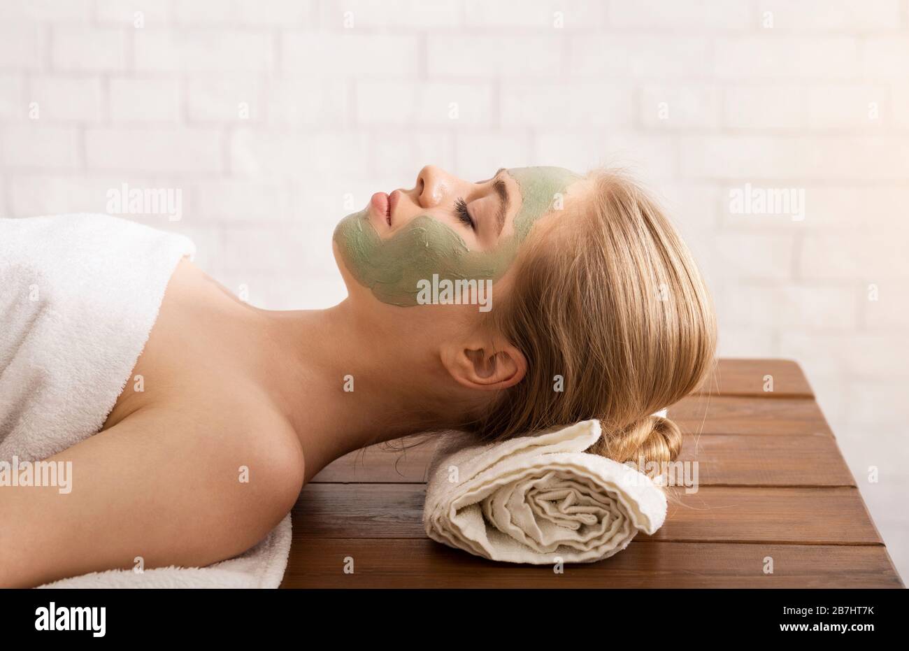 Donna millenaria in salone termale con maschera sul viso Foto Stock