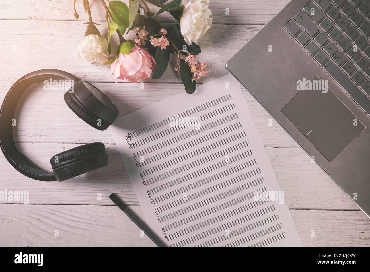 foglio di note musicali vuoto sul tavolo in legno con laptop e cuffie. vista dall'alto Foto Stock