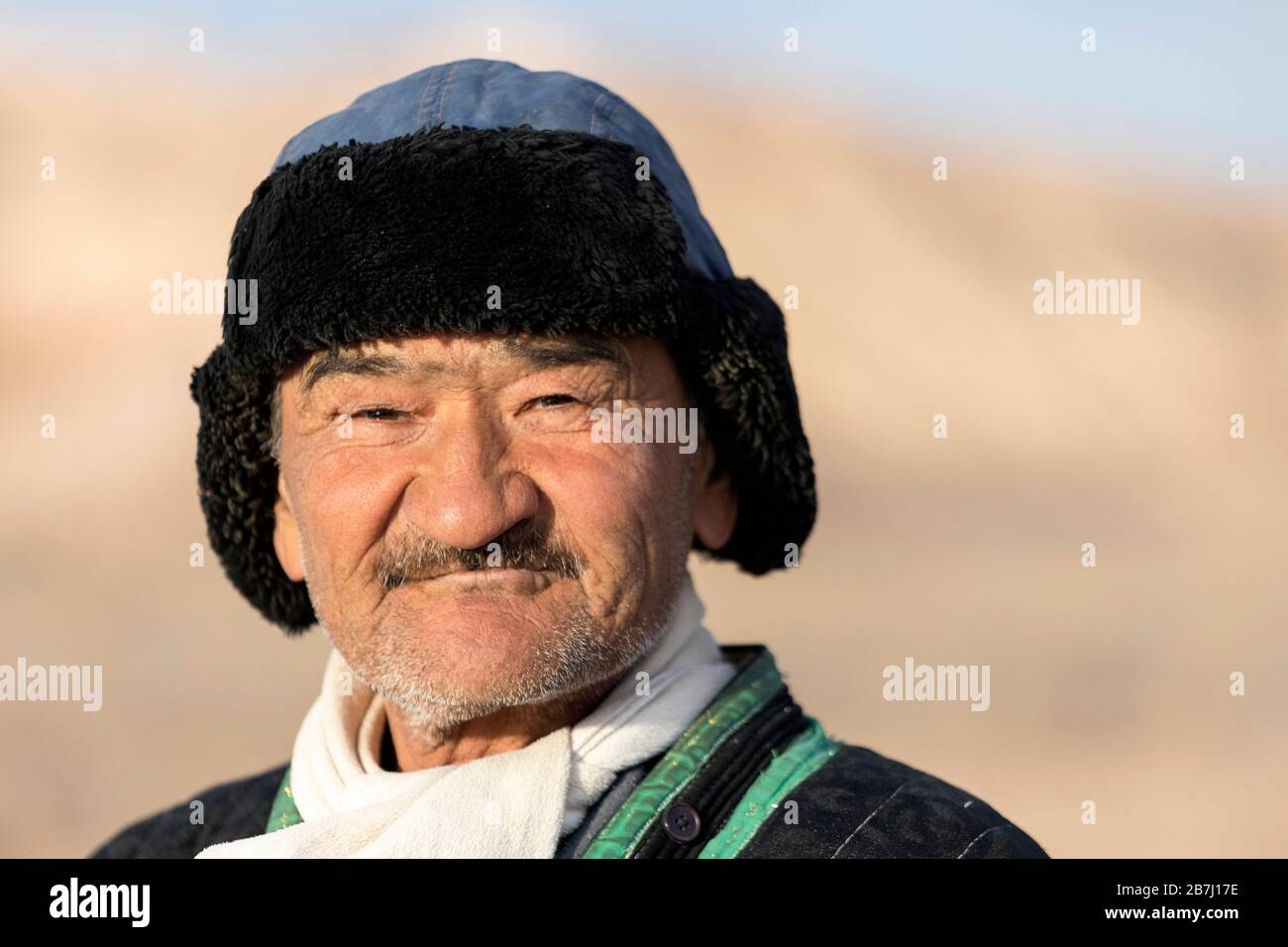 Ritratto di un simpatico pastore uzbeko in abiti tradizionali e un cappello di pelliccia, Ayaz Kala, Kyzylkum Desert, Karakalpakstan, Uzbekistan Foto Stock