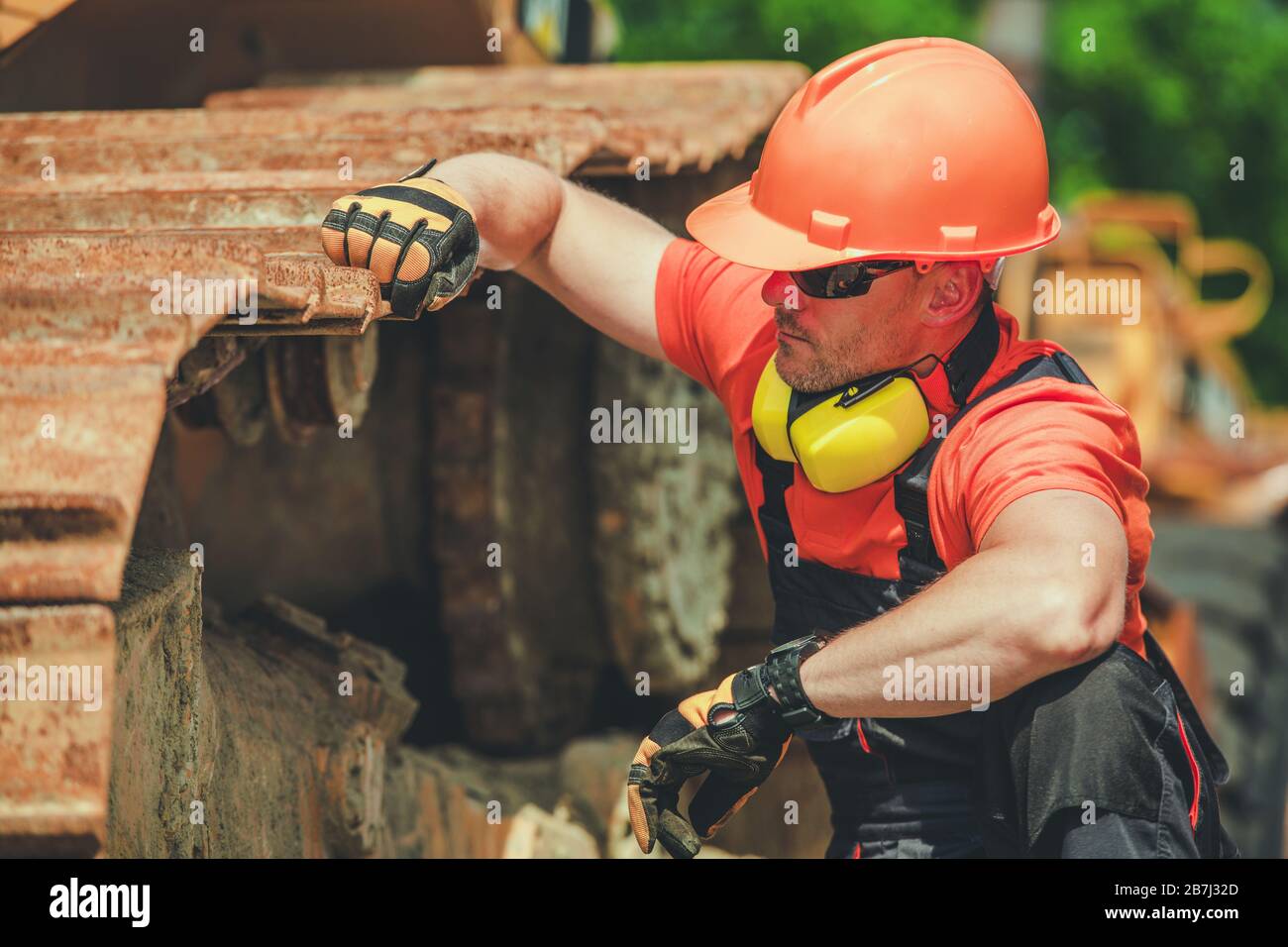 Lavoratore del lavoro di costruzione. Uomini caucasici che indossano un  casco rigido di sicurezza e un'attrezzatura di protezione dal rumore per  dare un'occhiata rapida ai cingoli Bulldozer Foto stock - Alamy
