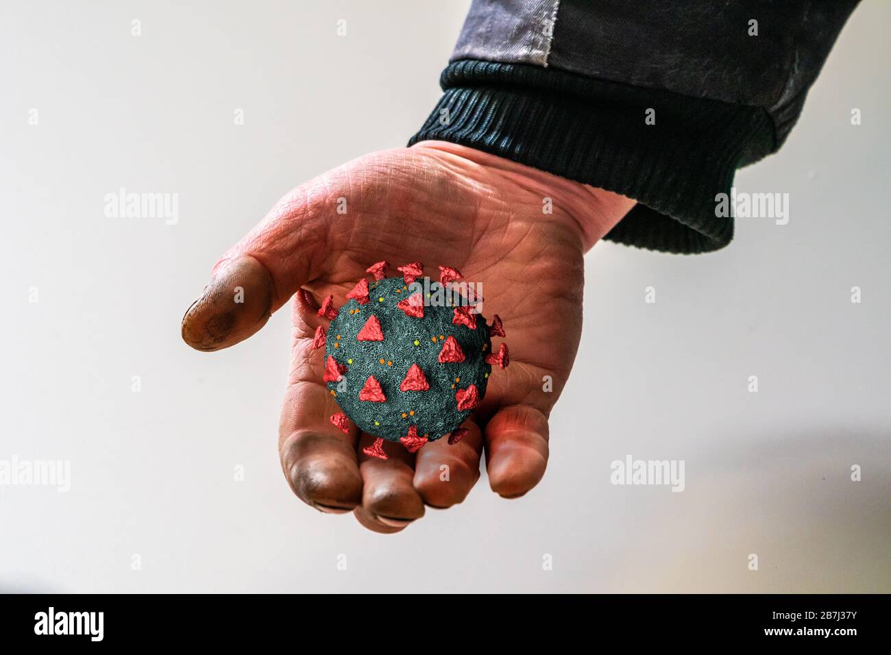 Uomo con sporca mano che tiene computer generato nuovo coronavirus 2019-nCoV covid-19. Protezione pandemica del virus e concetto di igiene. Foto Stock