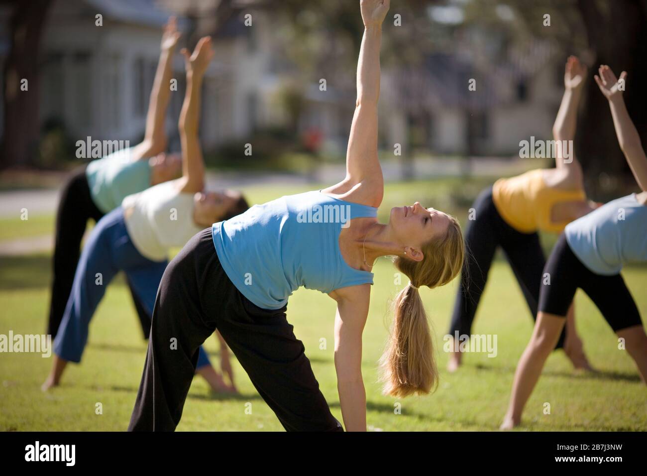 Metà donna adulta la pratica dello yoga con un gruppo di donne al di fuori. Foto Stock