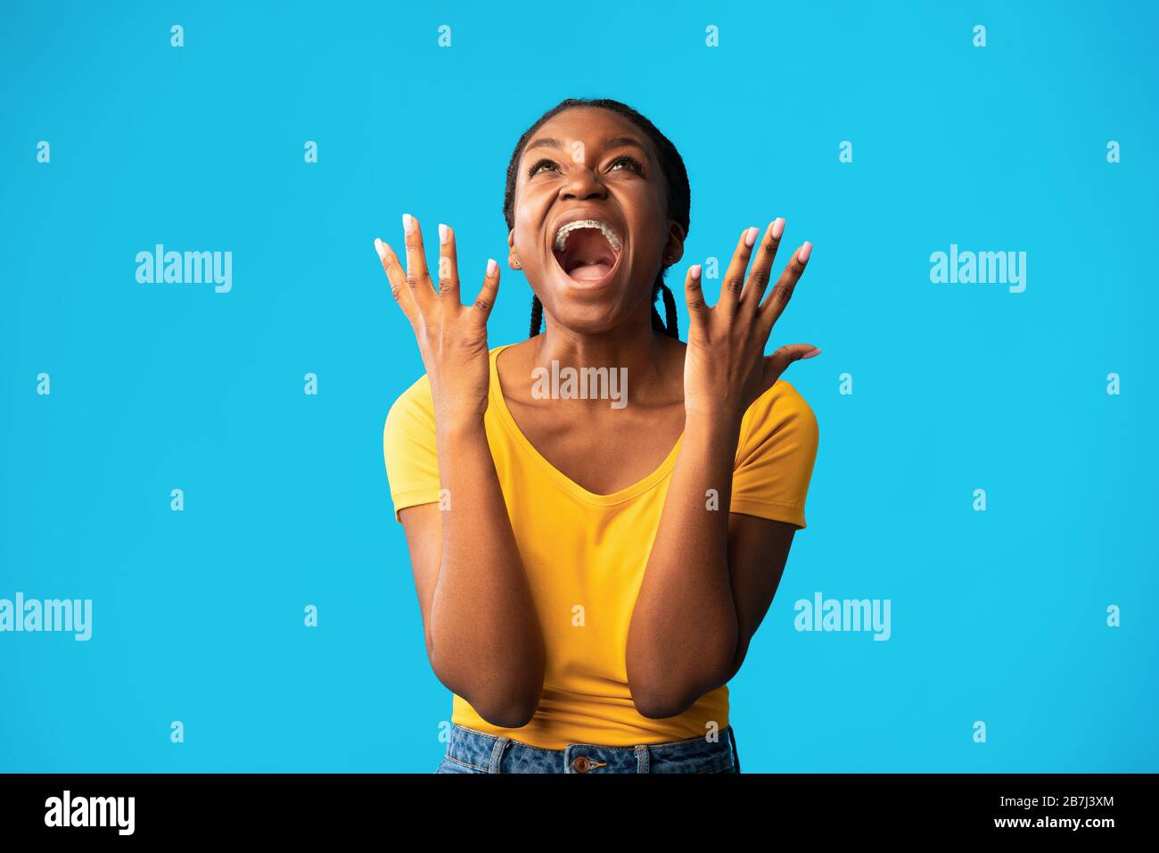 Emotivo African Woman gridando in piedi su sfondo blu, Studio Shot Foto Stock