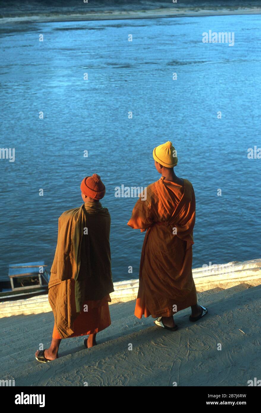 Due monaci buddisti in abiti arancioni si ergono sui gradini che conducono al fiume Mekong al tramonto a Luang Prabang, Laos. La città di Luang Prabang è patrimonio dell'umanità dell'UNESCO. Foto Stock