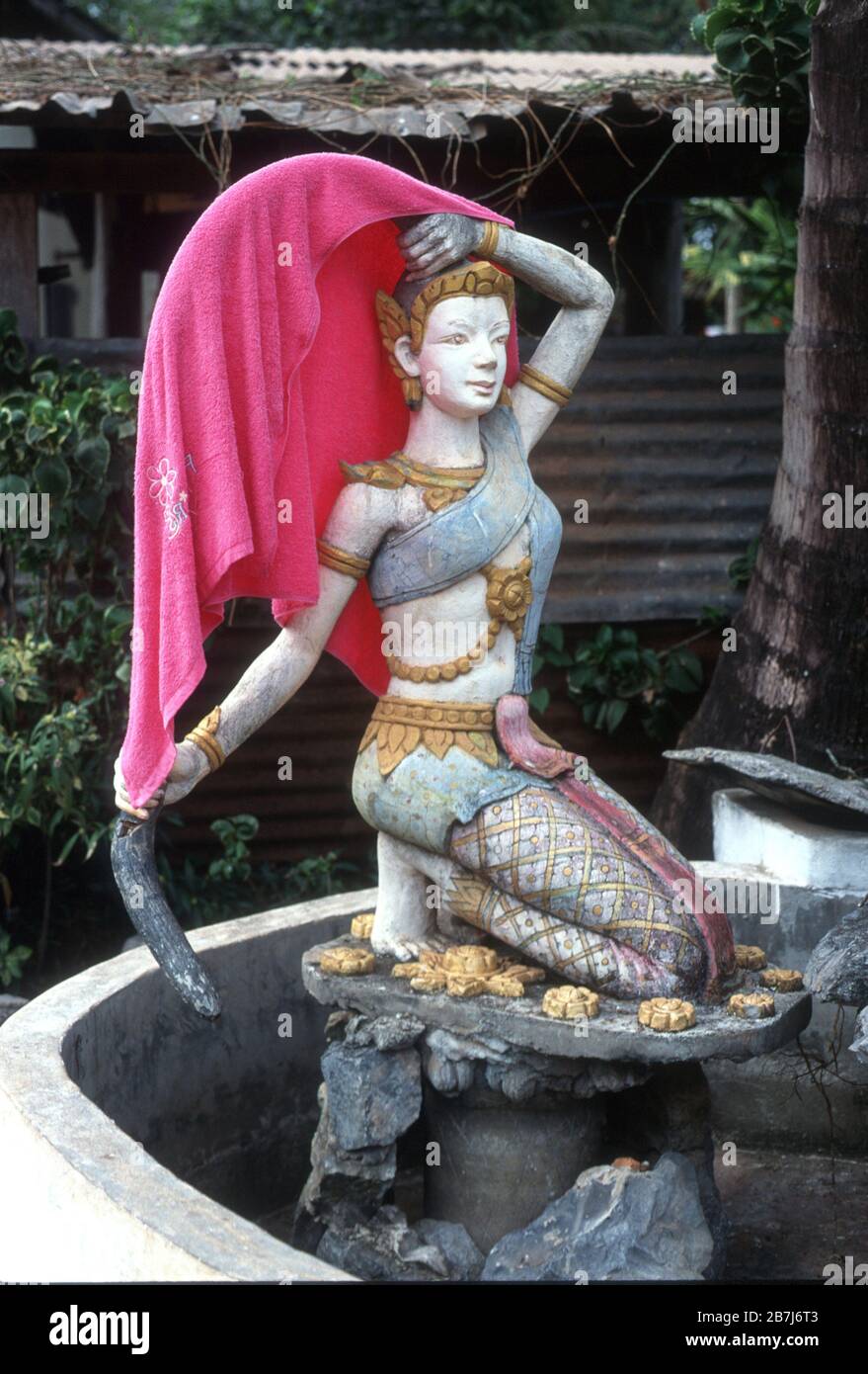 Scultura di una donna nei terreni di un tempio o wat a Vientiane, Laos - usato per asciugare un asciugamano rosa Foto Stock