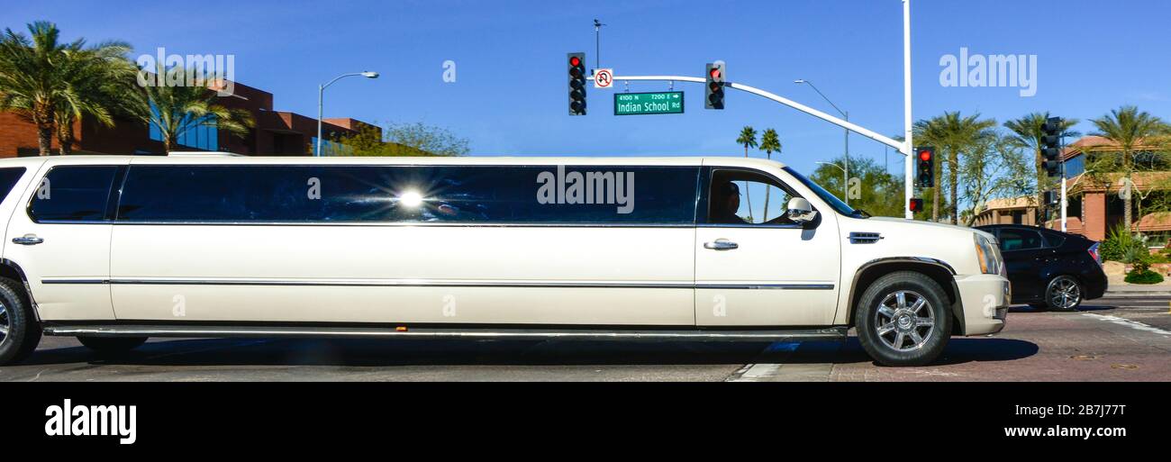 Una limousine bianca di Cadillac, che attraversa un incrocio tra Scottsdale e Indian School Roads con paesaggi desertici nell'esclusivo Scottsdale, Arizona Foto Stock
