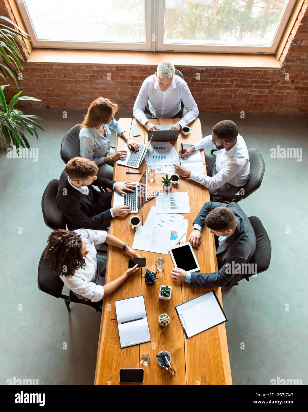 Collaboratori diversi che lavorano utilizzando computer seduti alla scrivania in ufficio Foto Stock