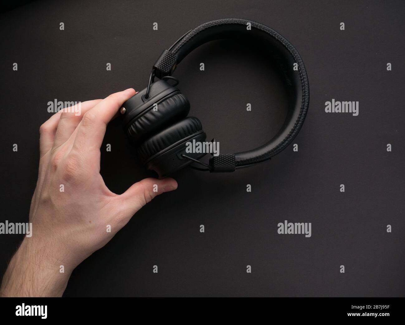 Cuffie wireless classiche nere su sfondo cartaceo colorato. Stile retrò. anni '80. Cultura pop. Vista dall'alto. Concetto di musica minimale Foto Stock