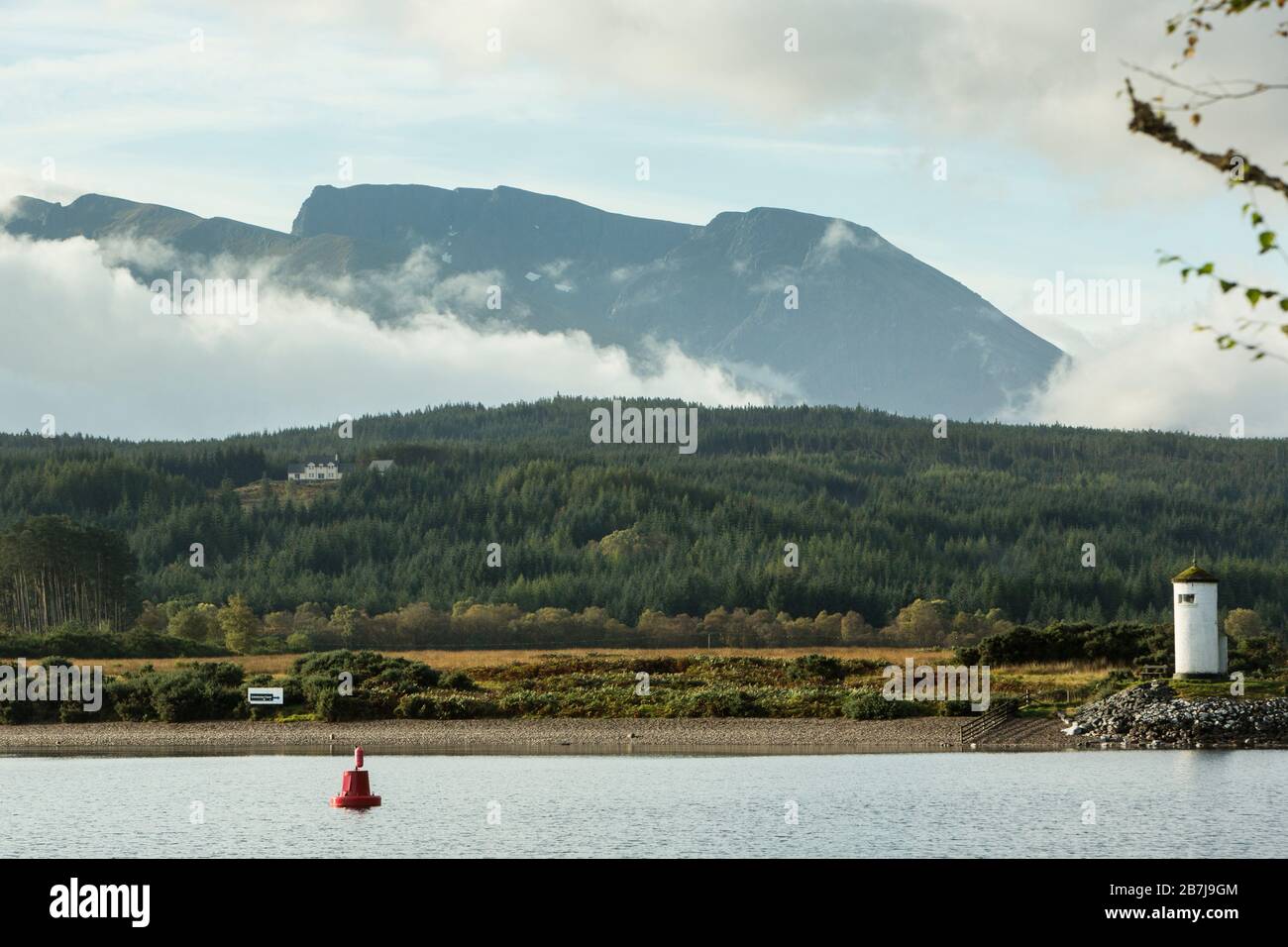 La faccia nord di ben Nevis, la montagna più alta del Britains, vista attraverso Loch Lochy dalla Great Glen Way con il faro di Gairlochy Pepperpot. Foto Stock