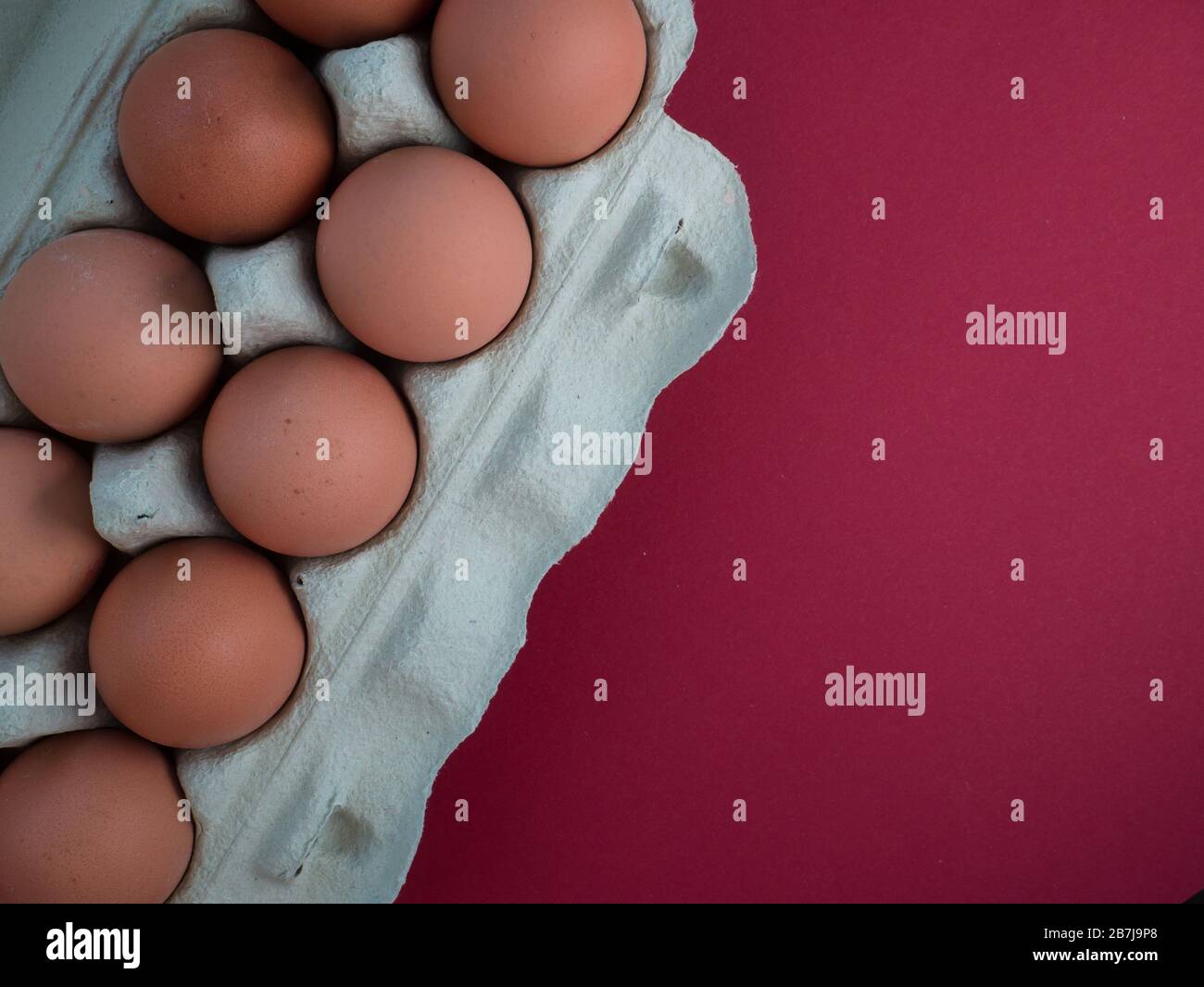 Vista dall'alto delle uova di pollo marroni in un cartone aperto isolato su rosso scuro. Uova di pollo fresche di fondo. Vista dall'alto con spazio di copia. Naturale Foto Stock