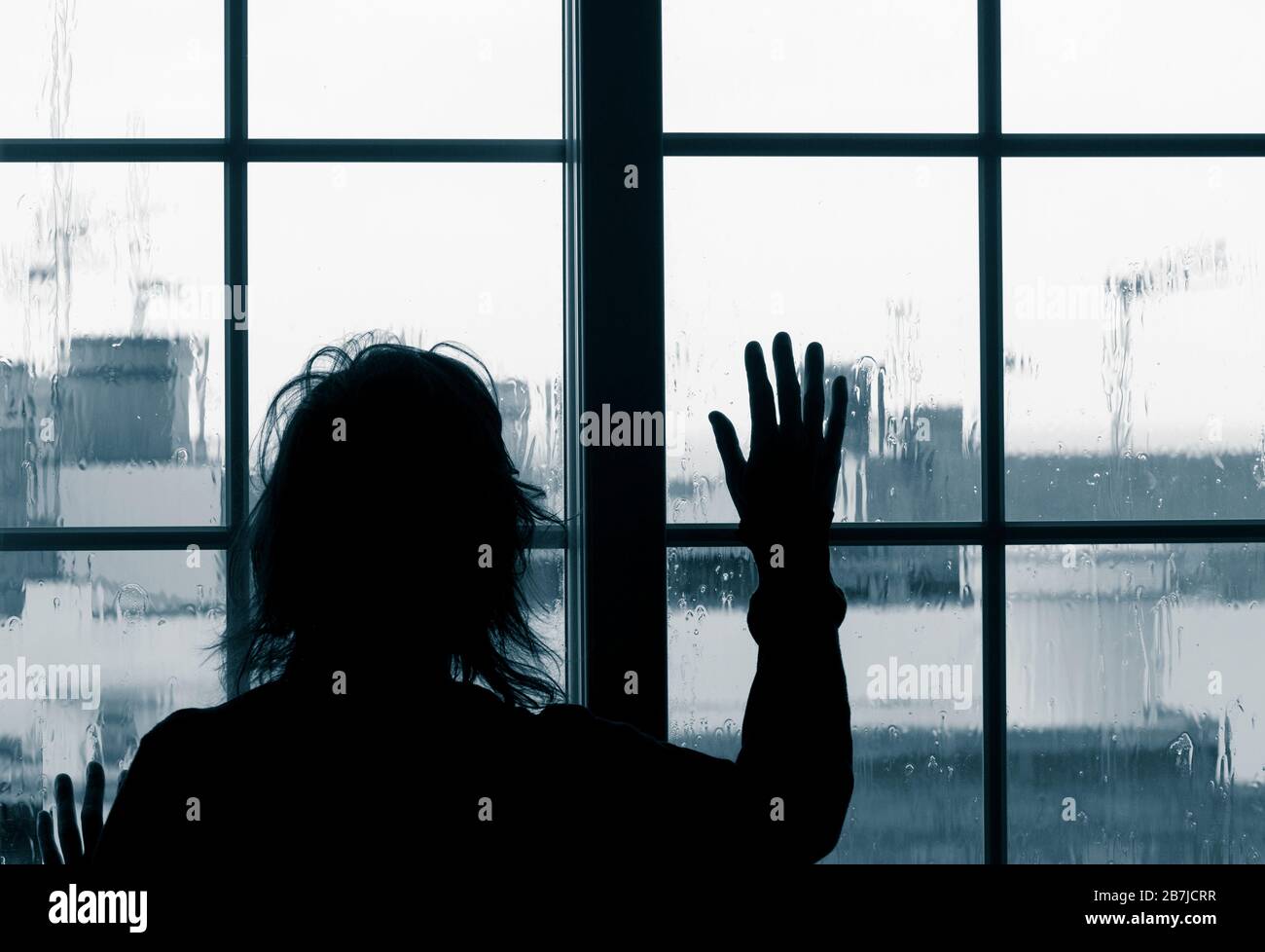 Donna che guarda fuori dalla finestra il giorno della pioggia. Immagine Conept; depressione femminile, abuso domestico, autoisolamento, quarantena, Coronavirus, Foto Stock